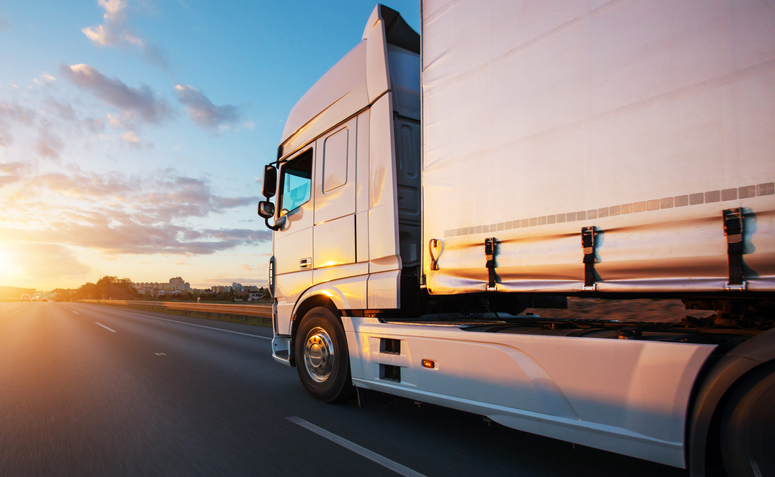 Loaded European truck on motorway in beautiful sunset light. On the road transportation and cargo.